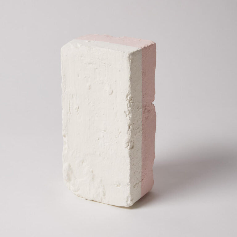 White brick with a pinkish-red interior on a light gray background