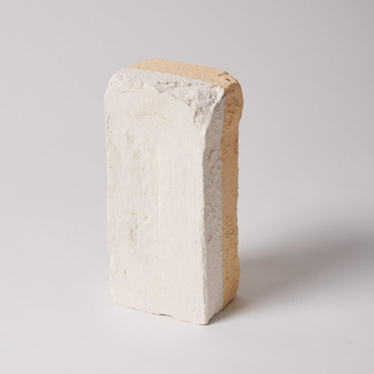Brick-like object with a textured surface on a light gray background