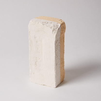 Brick-like object with a textured surface on a light gray background