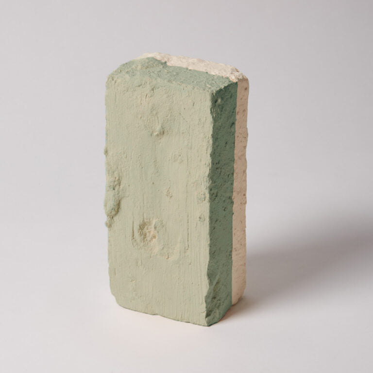 Three-layered brick with green, beige, and pink colors on a white background