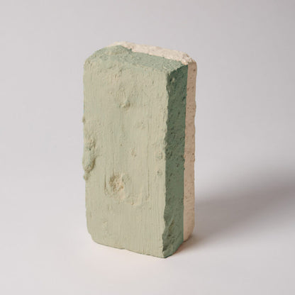 Three-layered brick with green, beige, and pink colors on a white background