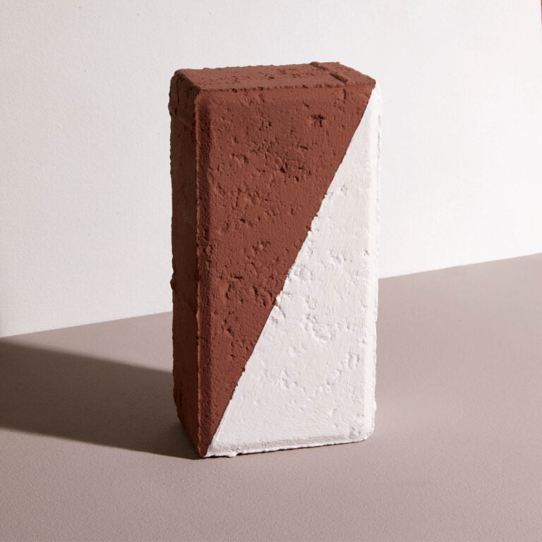 Triangular block with brown and white sides on a flat surface