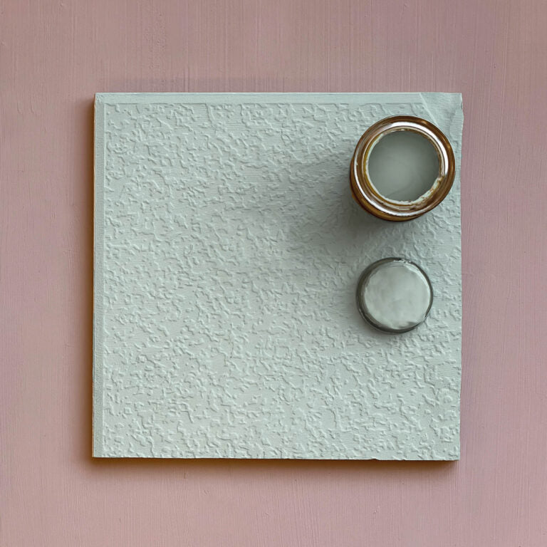 Textured square wall art with circular cutouts on a pink background