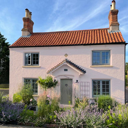 White house with a red tiled roof and garden in front