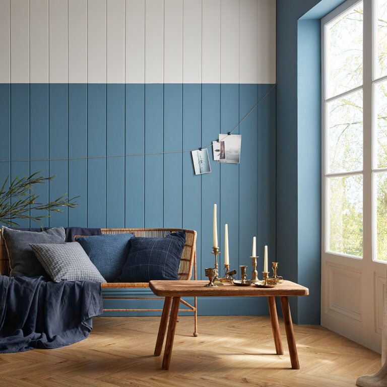 Modern living room with blue paneled wall, wooden sofa, and coffee table.