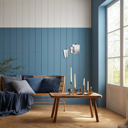Modern living room with blue paneled wall, wooden sofa, and coffee table.