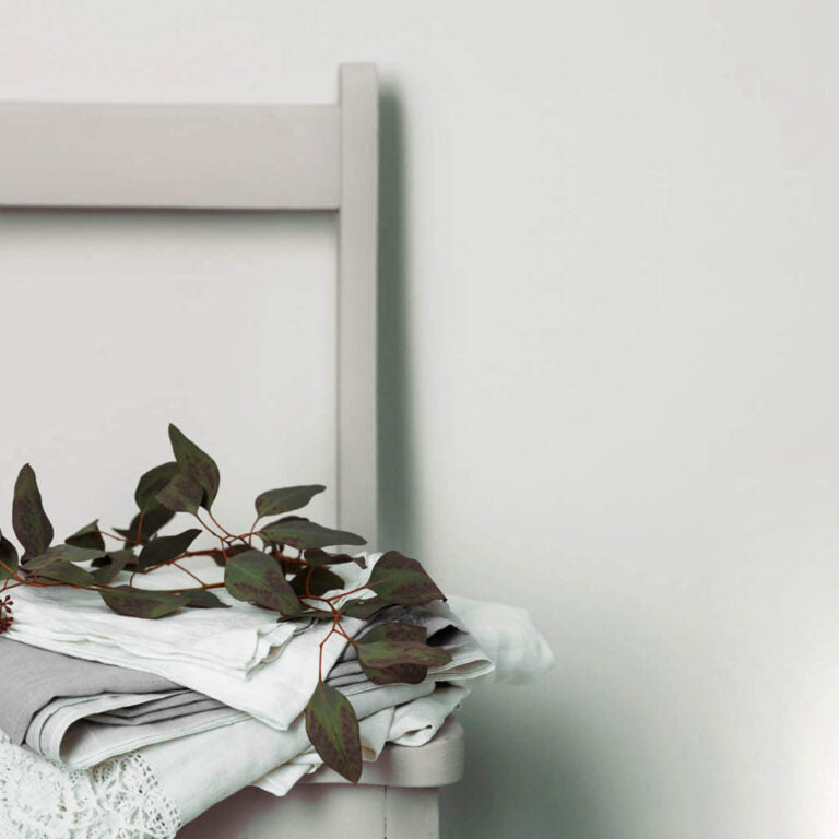 Stack of white towels with green leaves on a white surface