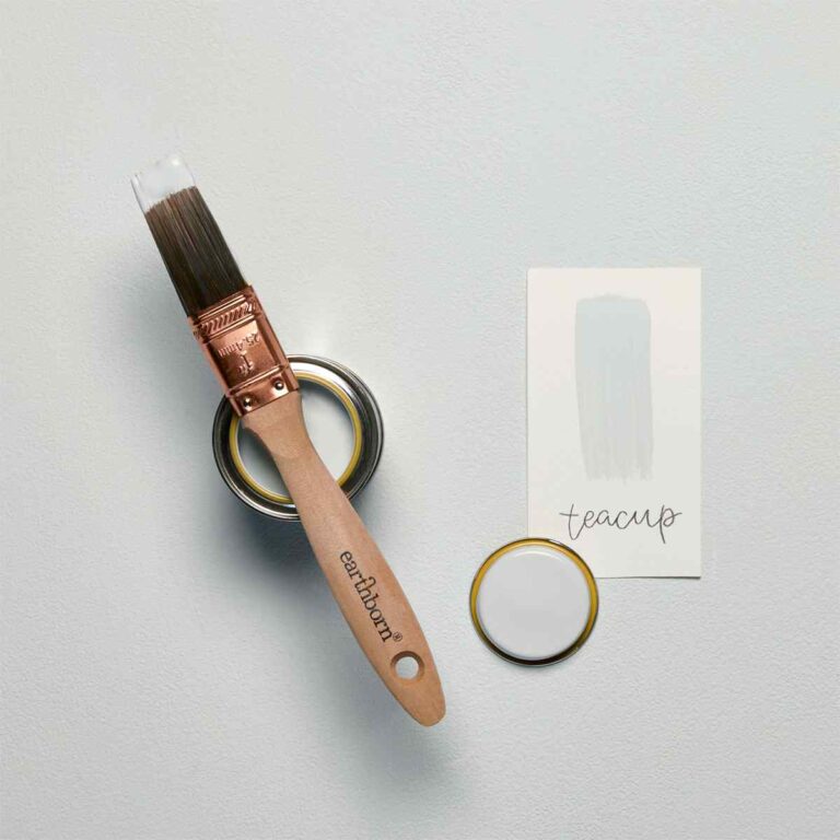 Paint brush with 'earthborn' branding next to a can of paint and a decorative ring on a light gray background.