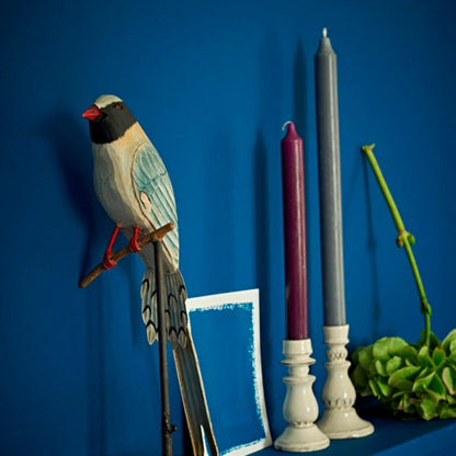 Decorative bird figurine, candles, and plant against a blue background