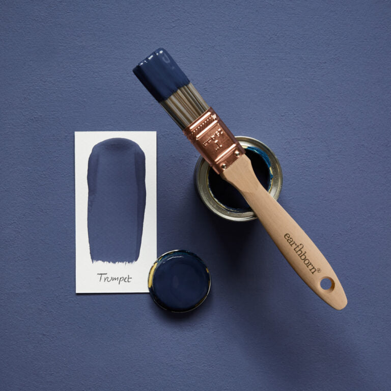 Paintbrush with blue paint and color swatch on a blue background