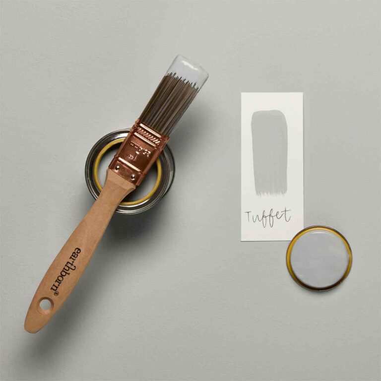 Paintbrush with a can of paint, a sample swatch, and a color card on a gray background