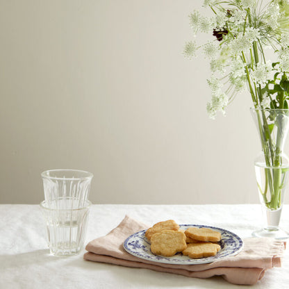 Table setting with cookies, glasses, and a vase of flowers on a neutral background