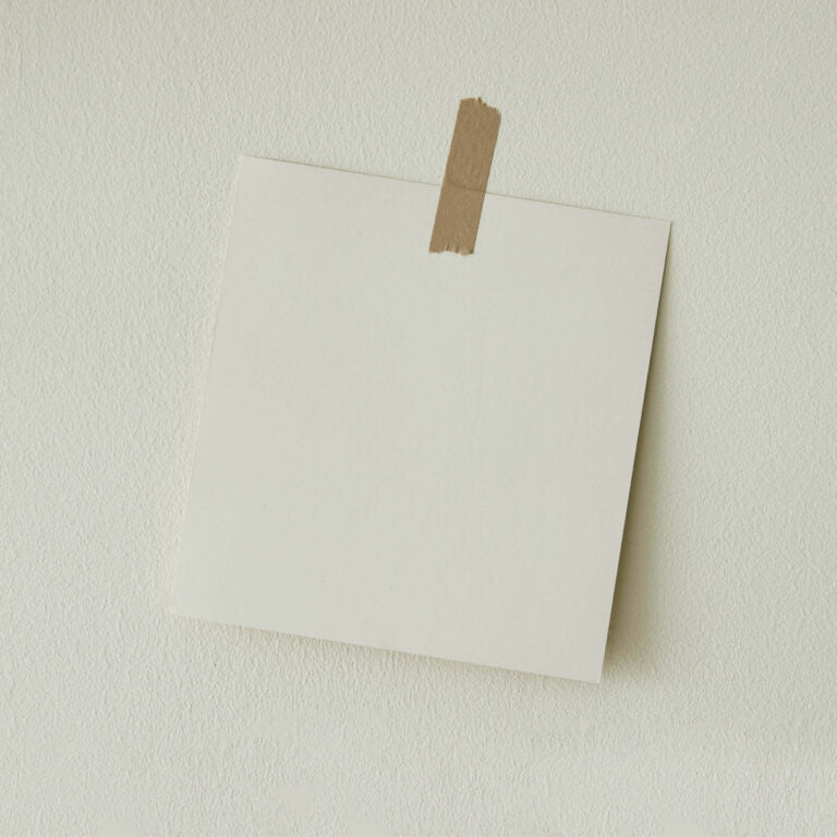 White paper attached to a beige wall with brown tape