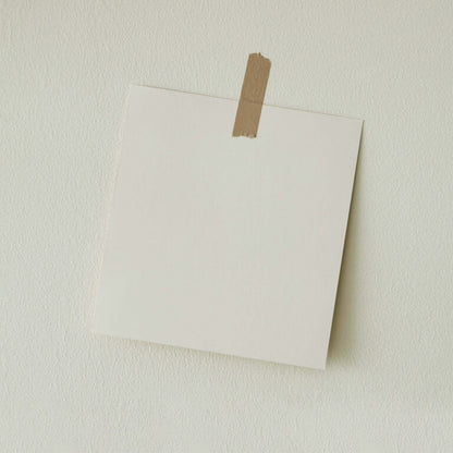 White paper attached to a beige wall with brown tape