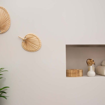 Woven wall art pieces on a light gray wall with a small shelf below.