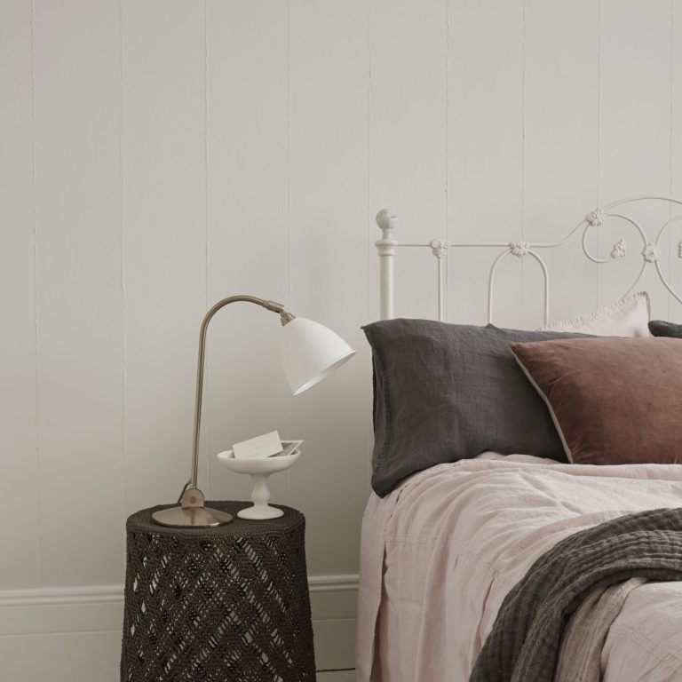 Bedroom with a bed featuring pillows and a side table with a lamp.