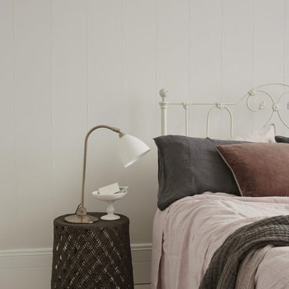 Bedroom with a bed featuring pillows and a side table with a lamp.