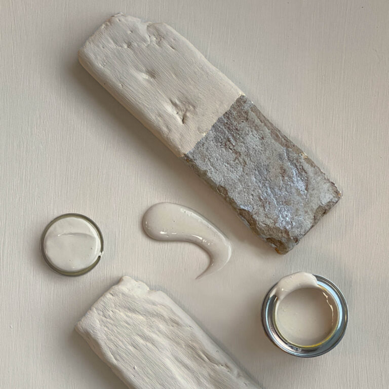 Two stone-like blocks with a small container of cream on a light background