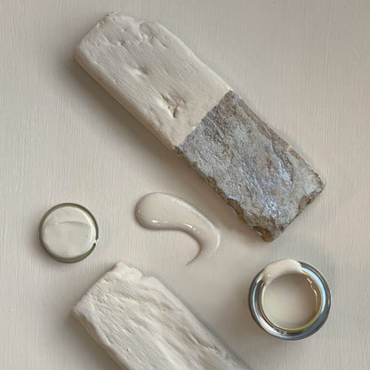 Two stone-like blocks with a small container of cream on a light background