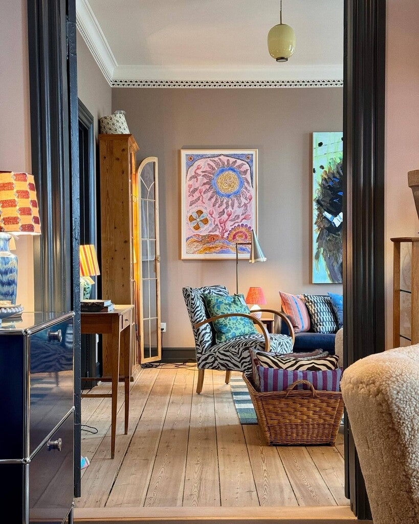 Living room with colorful decor, including a sofa, armchair, and artwork on the wall.