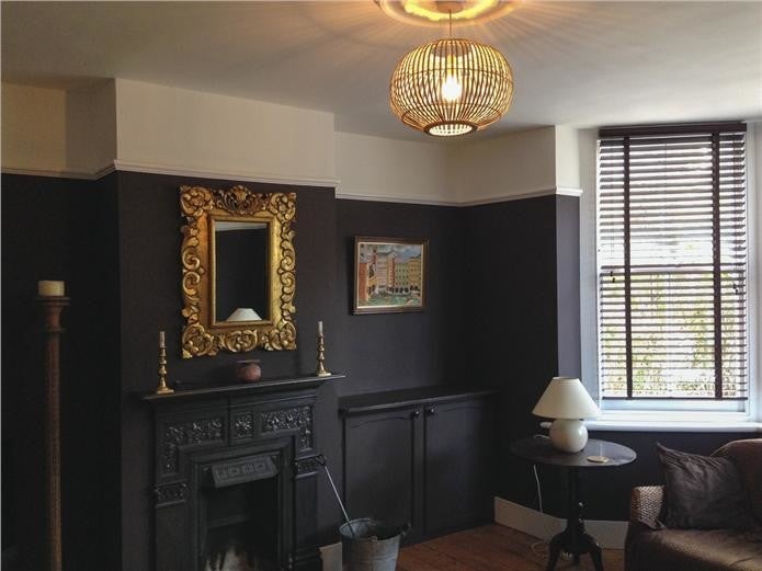 Living room with dark walls, fireplace, mirror, and window.