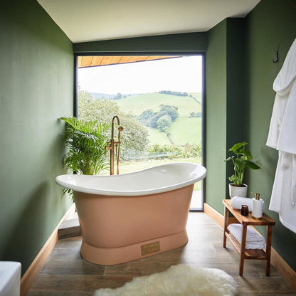 Bathroom with a freestanding bathtub, green walls, and a view of greenery outside.