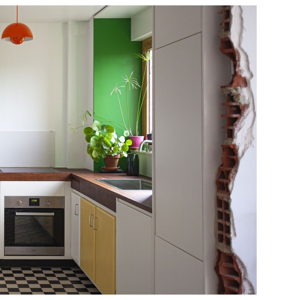 Modern kitchen with green wall, white cabinets, and a checkered floor.
