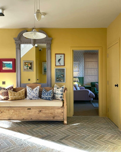 Living room with yellow walls, wooden bench, and decorative pillows.