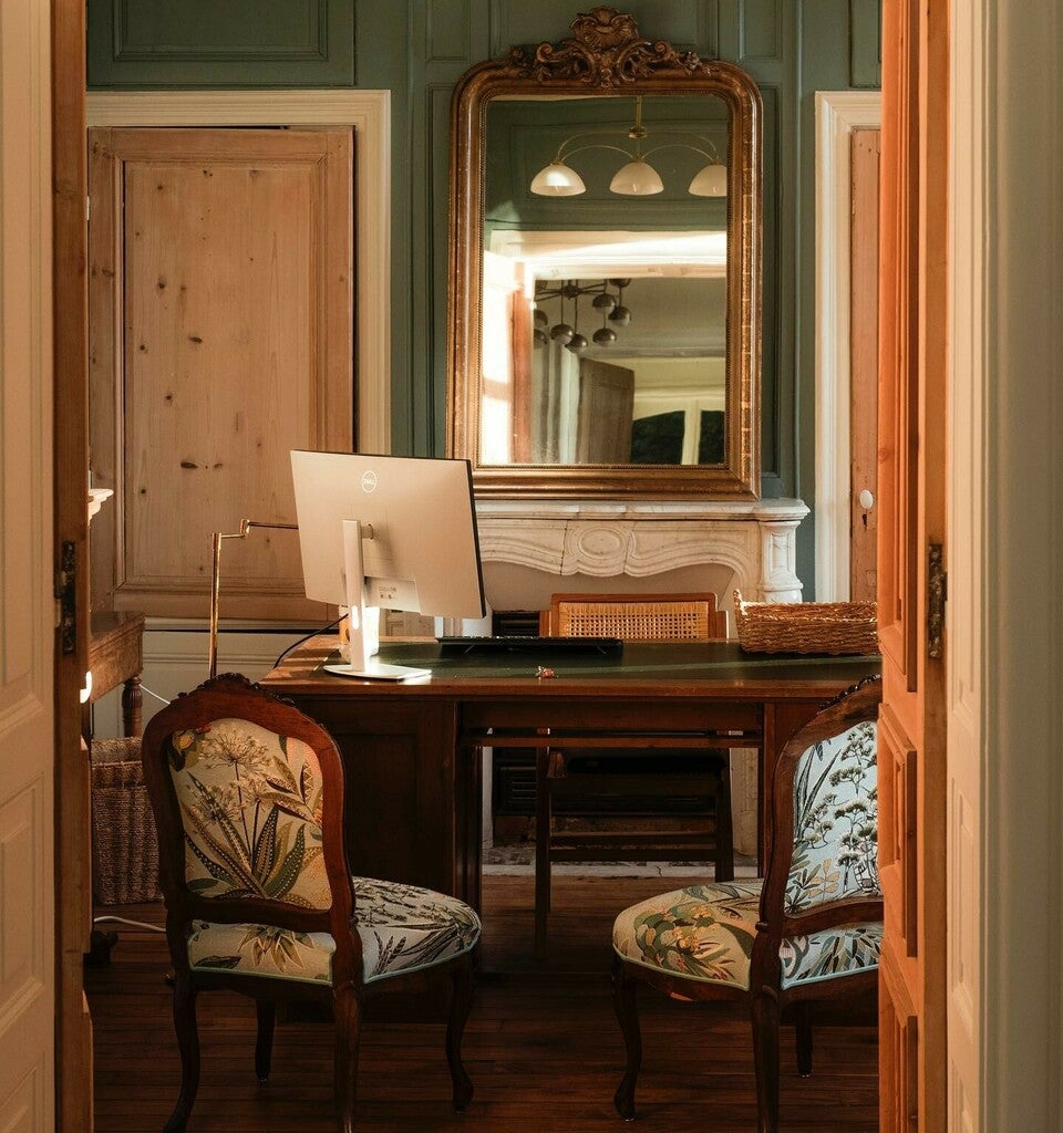 Vintage-style room with wooden desk, chair, and large mirror.