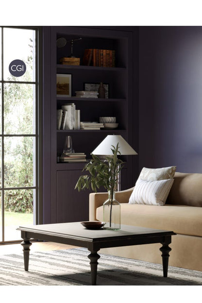 Living room with beige sofa, coffee table, and bookshelf against a dark wall.