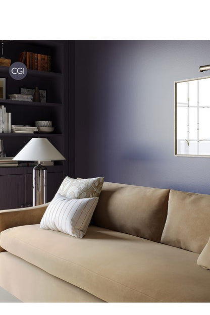 Beige sofa with decorative pillows in a room with a purple wall and a shelf.