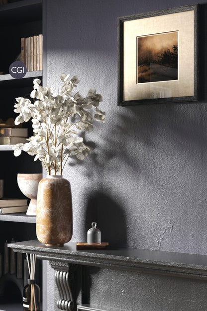 Decorative vase with flowers on a shelf against a gray wall with a framed picture.