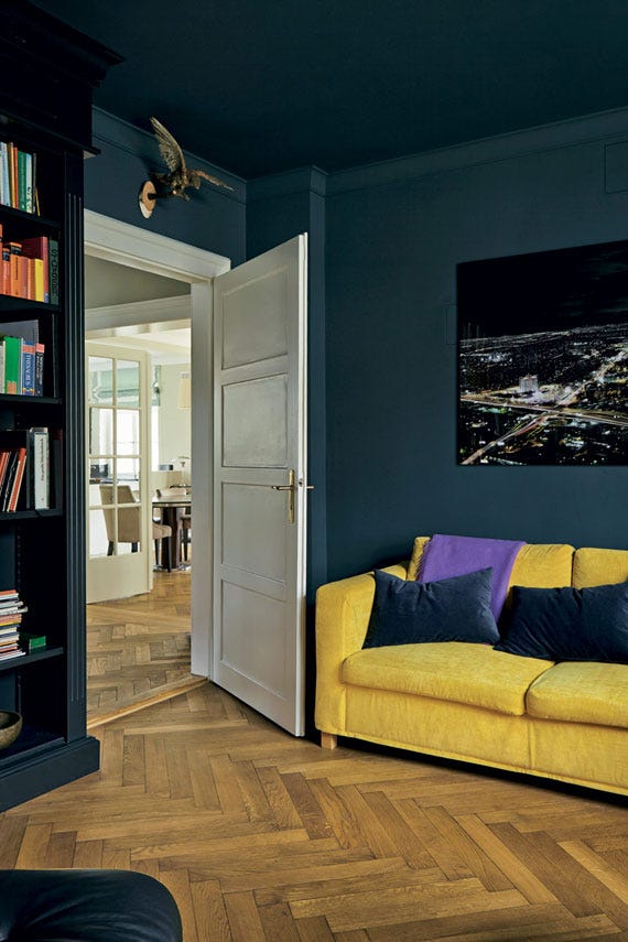 Living room with a yellow sofa, open door, and bookshelf.