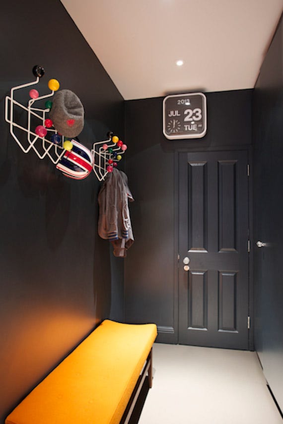 Modern hallway with a coat rack, bench, and door with a calendar.