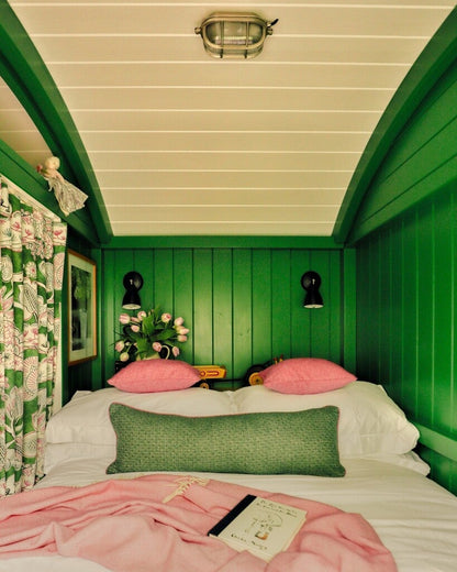 Bedroom with green walls, pink bedding, and decorative pillows.