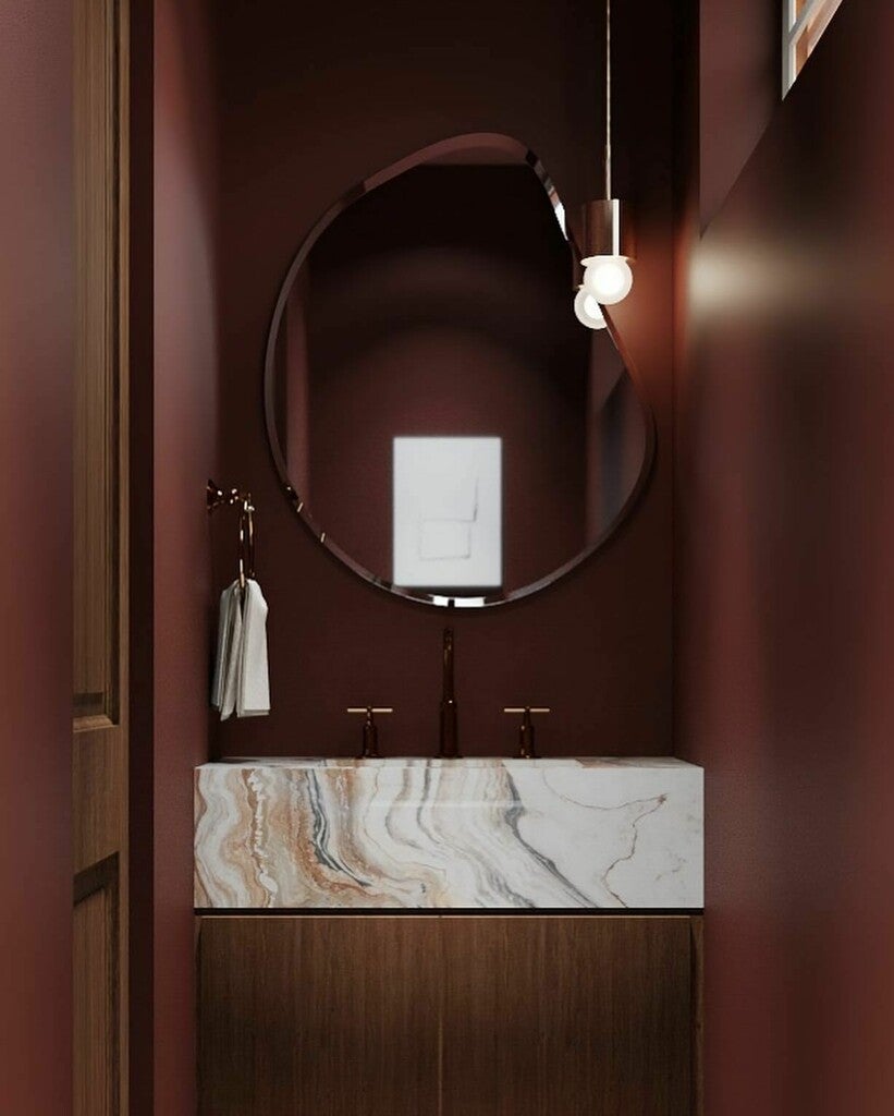 Bathroom vanity with marble countertop, round mirror, and pendant light.