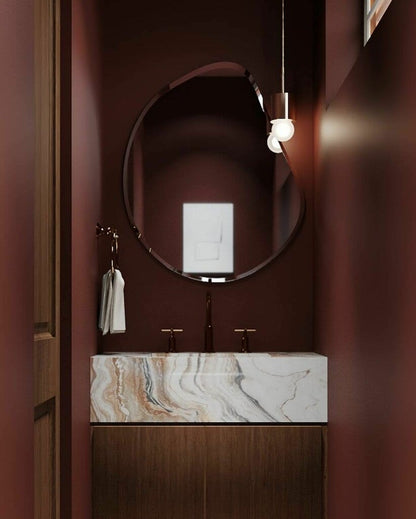 Bathroom vanity with marble countertop, round mirror, and pendant light.