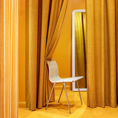 Chair in front of a large mirror with orange curtains