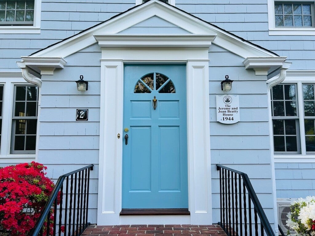 Blue front door of a house with decorative elements and flowers.