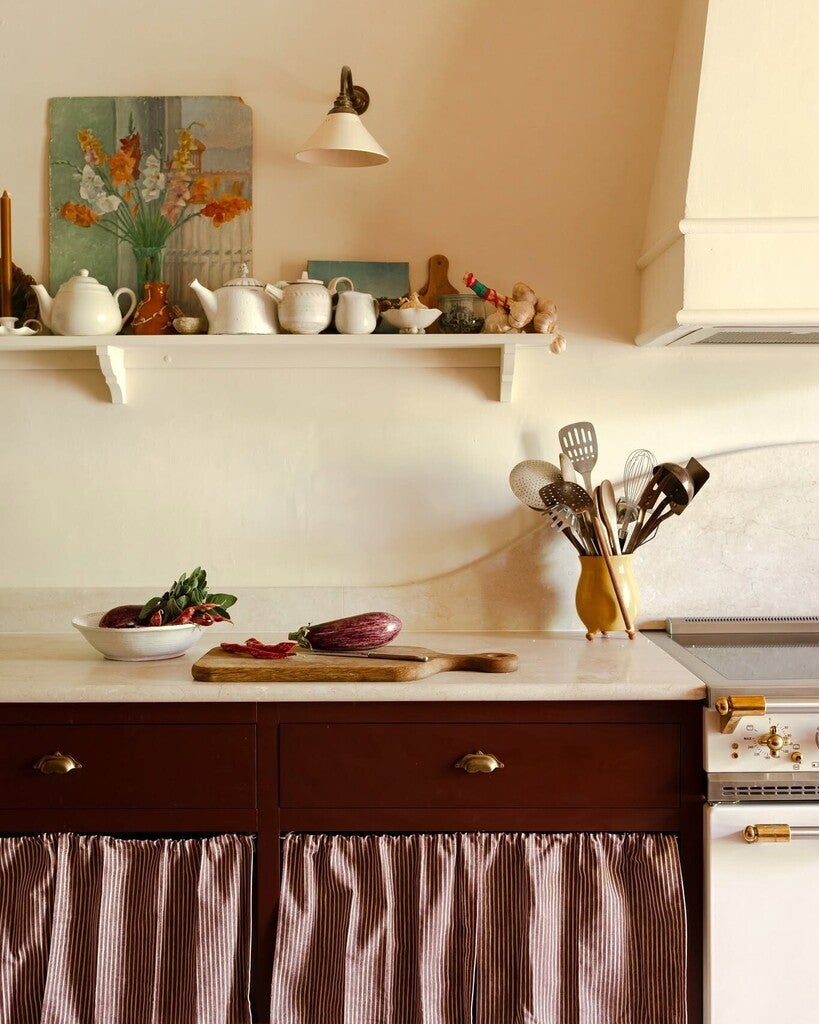 Kitchen counter with utensils, vegetables, and a shelf with decorative items.
