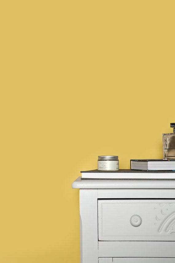 White dresser with decorative items against a yellow wall