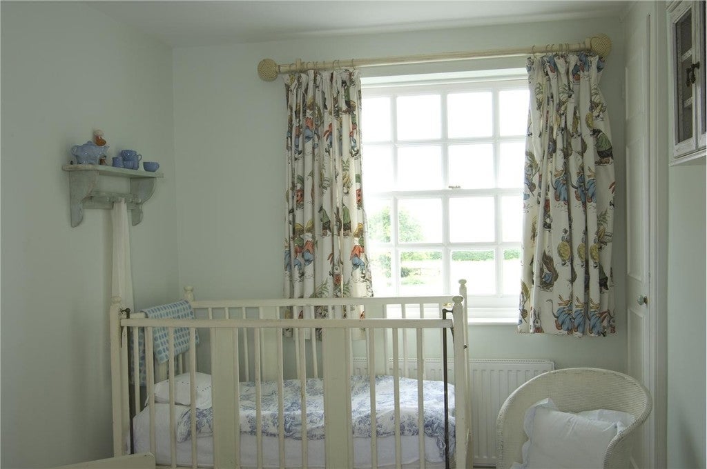 Nursery room with white crib, decorative curtains, and a window.