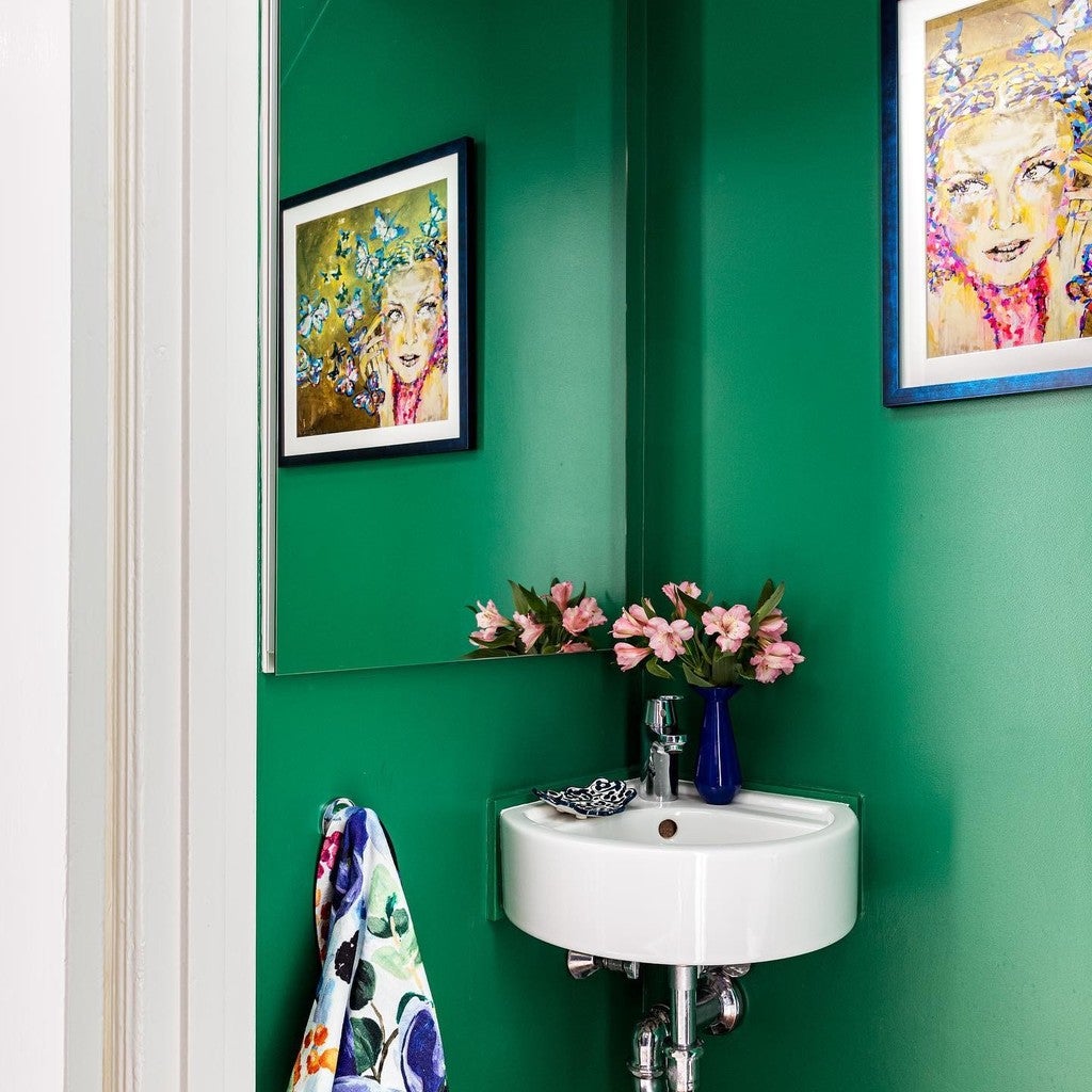 Bathroom with green walls, white sink, and floral decorations.