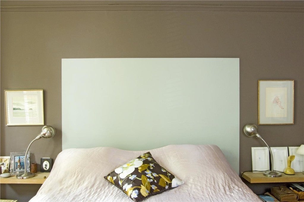Bedroom with a large white headboard, floral pillow, and two lamps on either side.