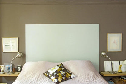Bedroom with a large white headboard, floral pillow, and two lamps on either side.