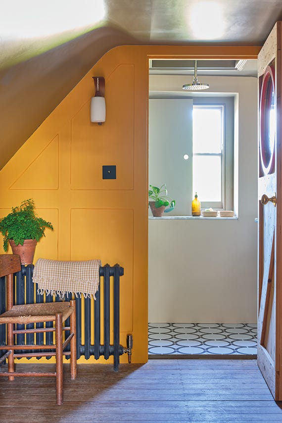 Narrow hallway with yellow wall, radiator, and window with plants.