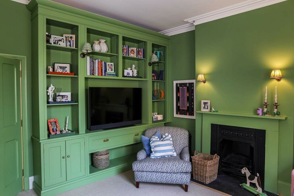 Green living room with bookshelf, TV, and armchair.
