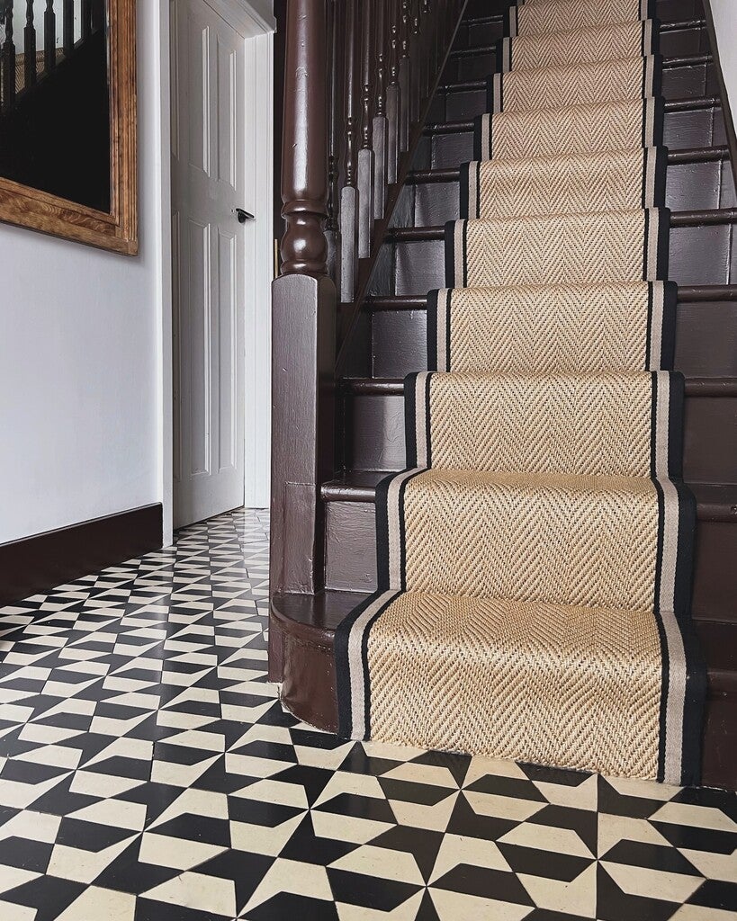 Staircase with a patterned runner on a black and white checkered floor.