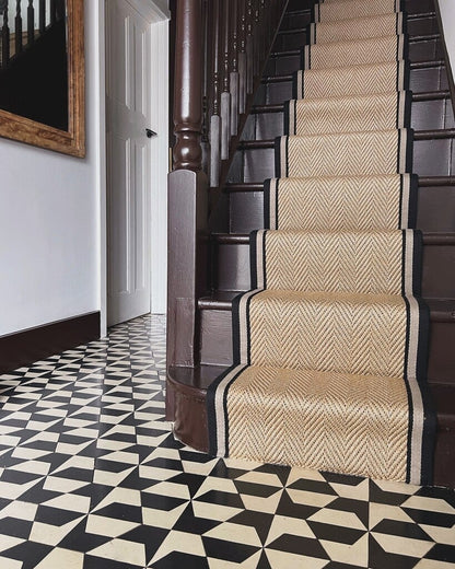 Staircase with a patterned runner on a black and white checkered floor.