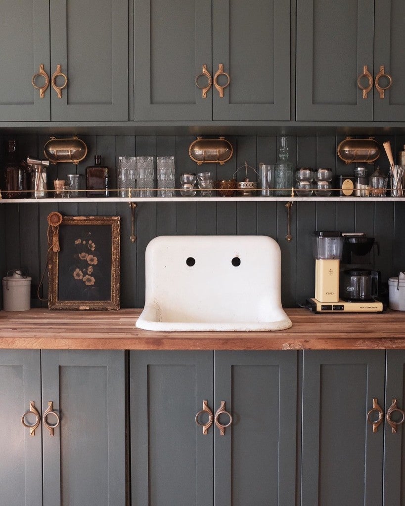 Kitchen with dark green cabinets, wooden countertops, and a white sink.
